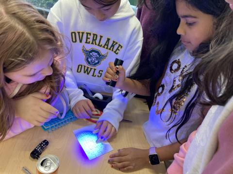 Students using a blacklight on a puzzle