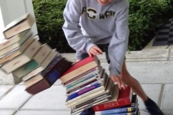 Boy tipping over stack of books