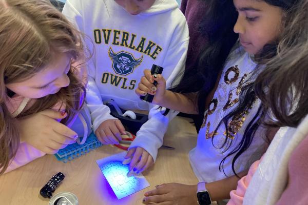 Students using a blacklight on a puzzle